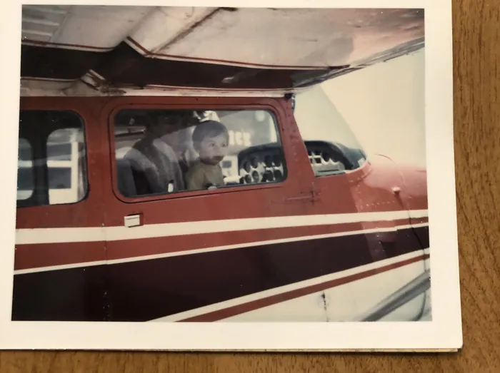 An old print of a small red and white airplane, from Frank's first flight