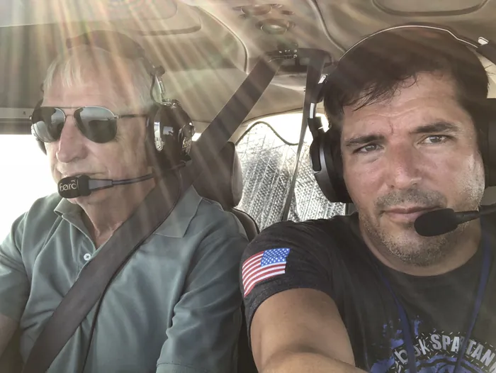 Frank Eskesen and his father wearing headsets in a small airplane cockpit