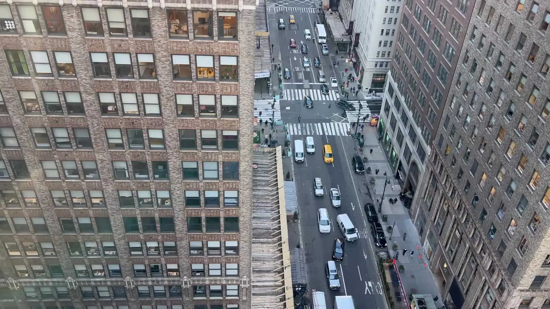 A Midtown Manhattan avenue seen from high above, with crosswalks and a yellow cab